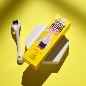 The Growth Bomb US Derma Roller, featuring 540 needles for scalp care and micro-needling, is displayed on a bright yellow background. The white roller is positioned next to its vibrant yellow packaging on a gray geometric surface.
