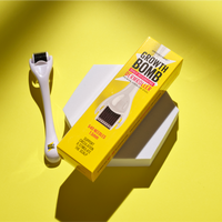 The Growth Bomb US Derma Roller, featuring 540 needles for scalp care and micro-needling, is displayed on a bright yellow background. The white roller is positioned next to its vibrant yellow packaging on a gray geometric surface.
