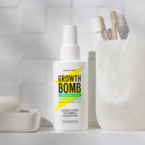 The Rescue, Restore & Hydrate Bundle by Growth Bomb US sits on a bathroom counter, accompanied by two wooden toothbrushes in a marble holder. The white tiles enhance the clean and simple aesthetic, perfectly showcasing your ultimate rescue remedy.
