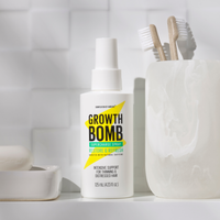 The Rescue, Restore & Hydrate Bundle by Growth Bomb US sits on a bathroom counter, accompanied by two wooden toothbrushes in a marble holder. The white tiles enhance the clean and simple aesthetic, perfectly showcasing your ultimate rescue remedy.