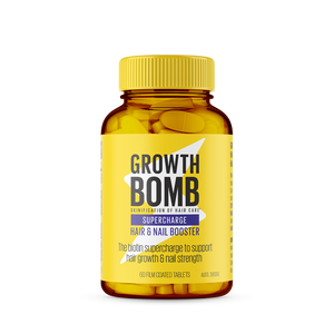 The image shows a Growth Bomb US Hair & Nail Booster Supplement. The amber bottle, featuring a yellow cap and label, highlights the biotin and cysteine support for hair growth and nail strength. The product contains 60 film-coated tablets.