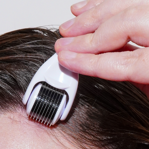 White derm roller comb pressed onto scalp with fingers