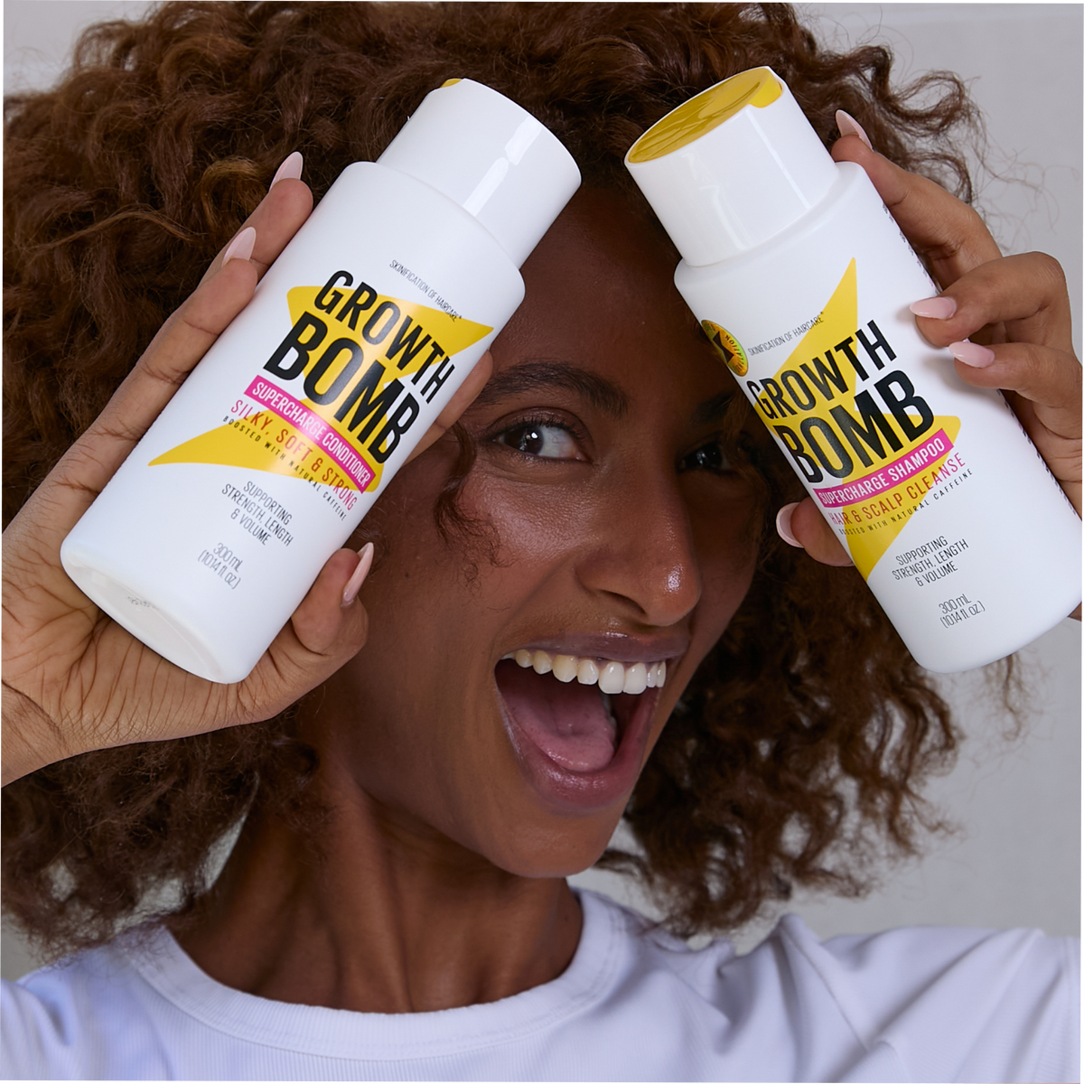 Two hair care bottles held near face with yellow and black Growth Bomb labels
