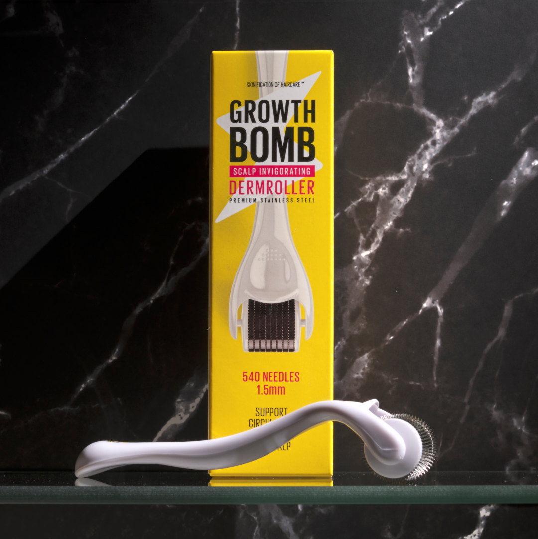 A white Growth Bomb US Derma Roller with a metal needle head is set against a dark marble backdrop, in front of its yellow box. Perfect for scalp care, the box emphasizes 540 needles and a 1.5mm size for invigorating micro-needling treatments.