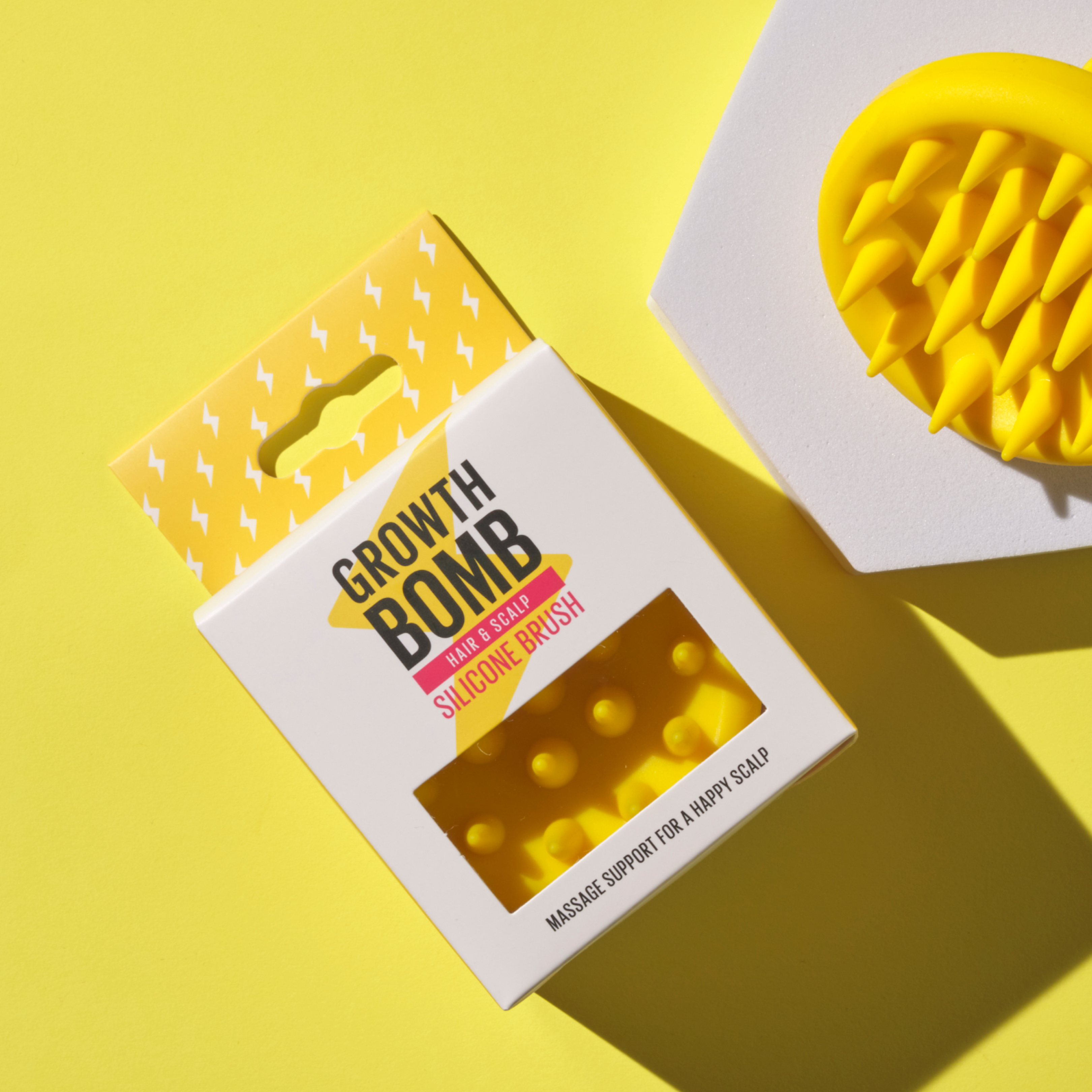 Silicone scalp brush, yellow bristles with Growth Bomb logo in open box