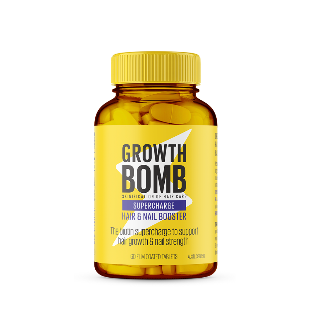 The image shows a Growth Bomb US Hair & Nail Booster Supplement. The amber bottle, featuring a yellow cap and label, highlights the biotin and cysteine support for hair growth and nail strength. The product contains 60 film-coated tablets.