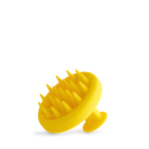 The Growth Bomb Silicone Scalp Brush is yellow with a handle, featuring soft spikes for hair and scalp exfoliation, shown on a white background.